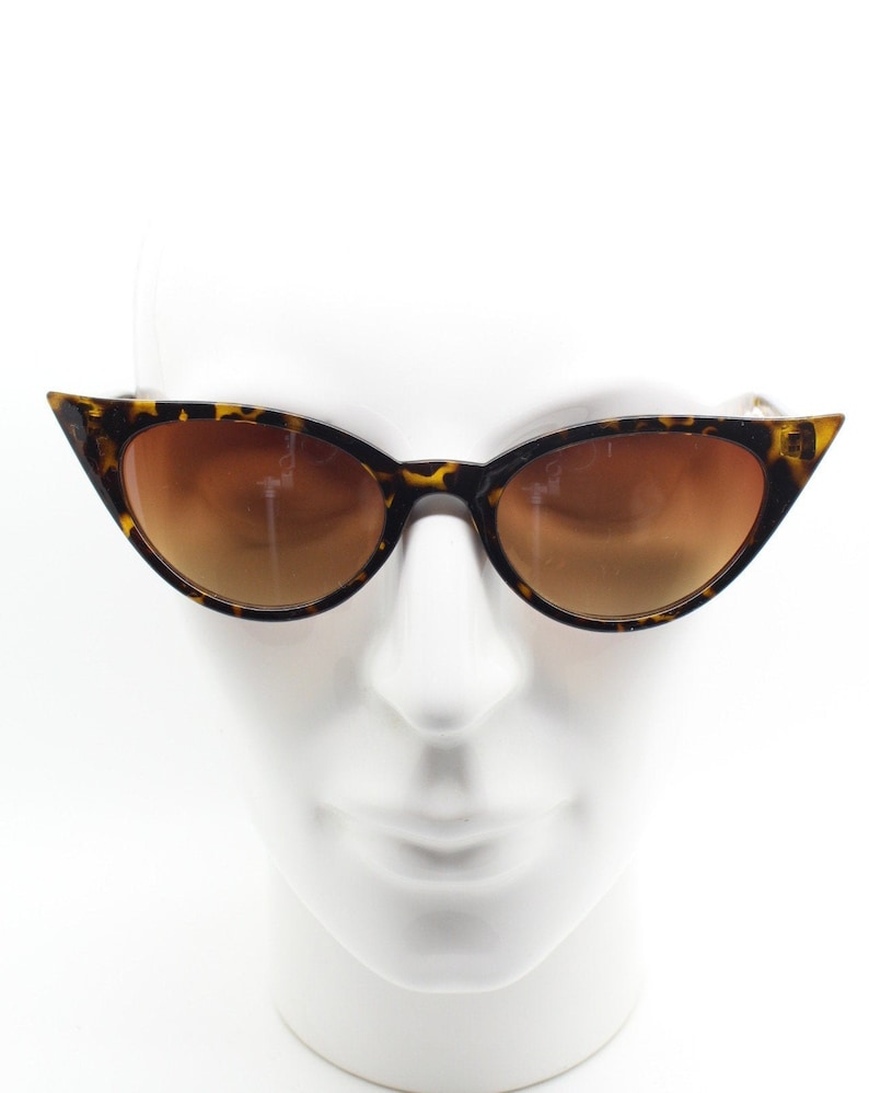 May include: Tortoise shell cat eye sunglasses with brown lenses. The sunglasses are on a white mannequin head.