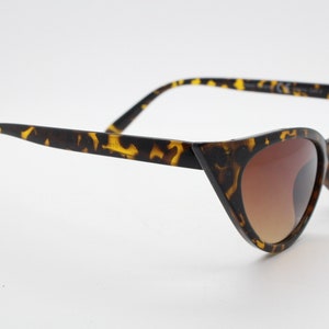 May include: Tortoiseshell cat eye sunglasses with brown gradient lenses.