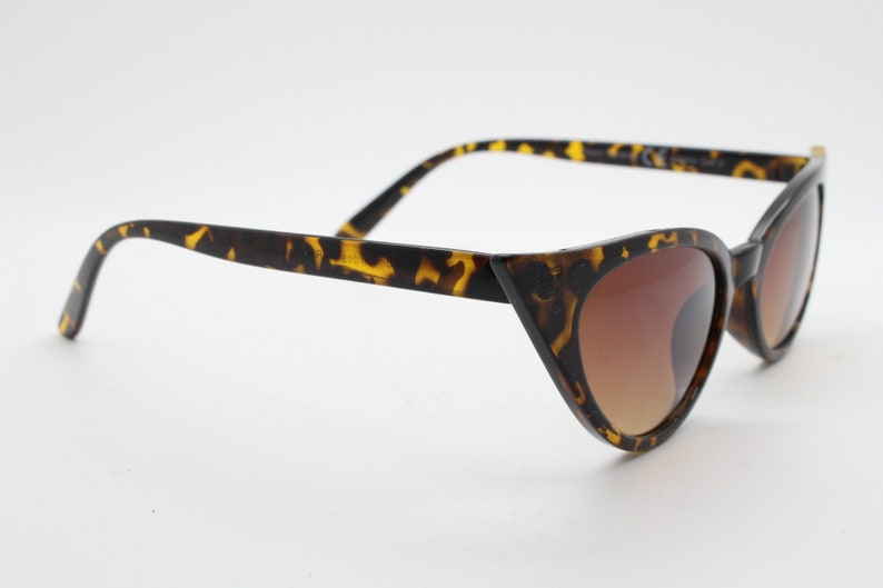 May include: Tortoiseshell cat eye sunglasses with brown gradient lenses.
