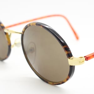 90s vintage oval sunglasses. Handsome honey tortoise and blazing amber arm combo on a slender metal frame. NOS