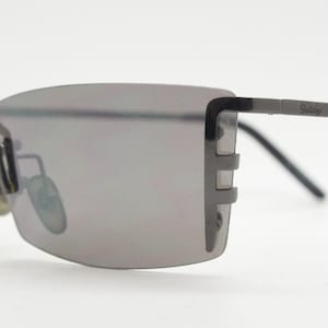 Y2K vintage wraparound sunglasses. Dynamic frameless shield design in gunmetal grey with slight mirror glaze rectangular lenses. 2000&#39;s NOS