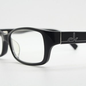 May include: Black rectangular eyeglasses with clear lenses and a silver CK logo on the side.