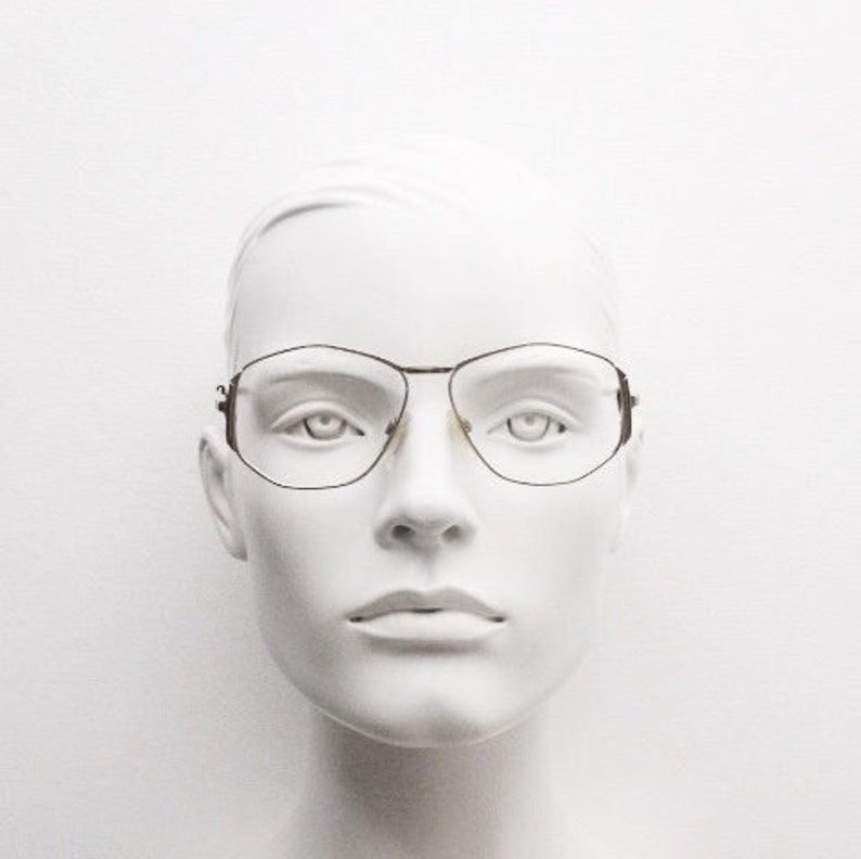 Puede incluir: Una cabeza de maniqu&iacute; blanca que lleva unas gafas finas con montura met&aacute;lica de forma rectangular.