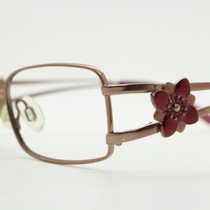 May include: Rose gold eyeglasses with a red flower detail on the right temple arm. The brand name "MISSONI" is engraved on the temple arm.