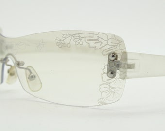 May include: Clear plastic sunglasses with a floral design etched into the frames.