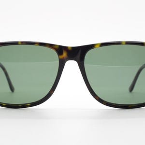 Puede incluir: Gafas de sol de carey con lentes verdes. Las gafas tienen una forma rectangular cl&aacute;sica.