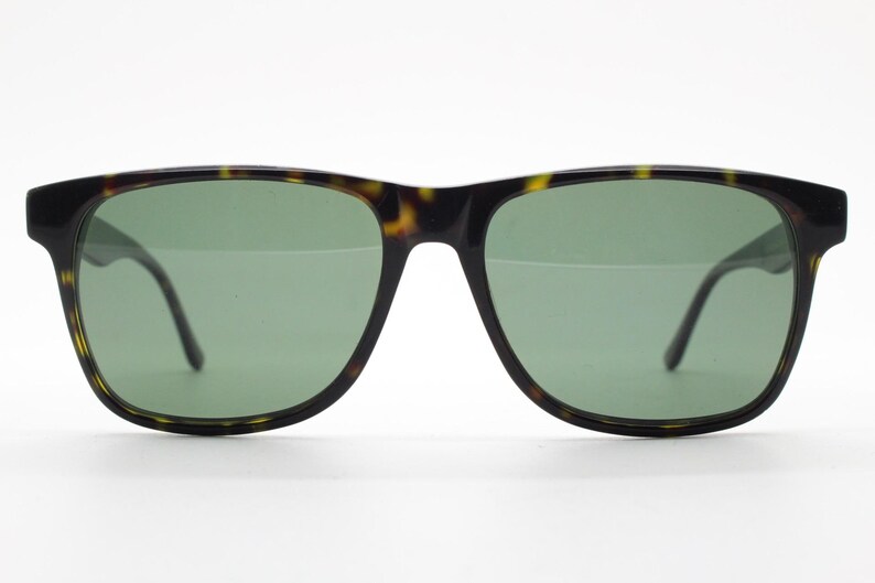 Puede incluir: Gafas de sol de carey con lentes verdes. Las gafas tienen una forma rectangular cl&aacute;sica.