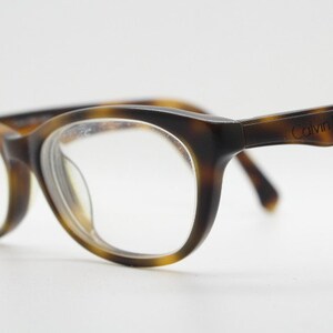 May include: Tortoiseshell eyeglasses with clear lenses and the text "Calvin Klein Jeans" on the right arm.