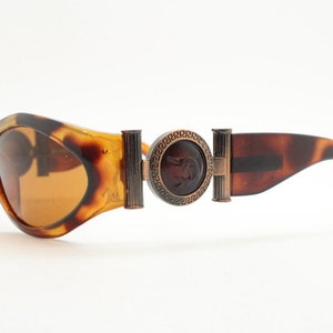 90s vintage oval sunglasses. Low profile transparent tortoise frame with massive bronze metal arm crests BNWT. Unused NOS