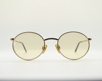May include: A pair of round, gold-rimmed eyeglasses with clear lenses.