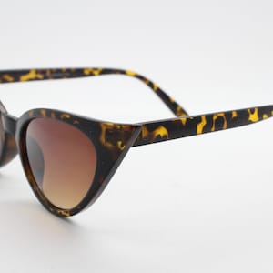 May include: Tortoise shell cat eye sunglasses with brown gradient lenses.