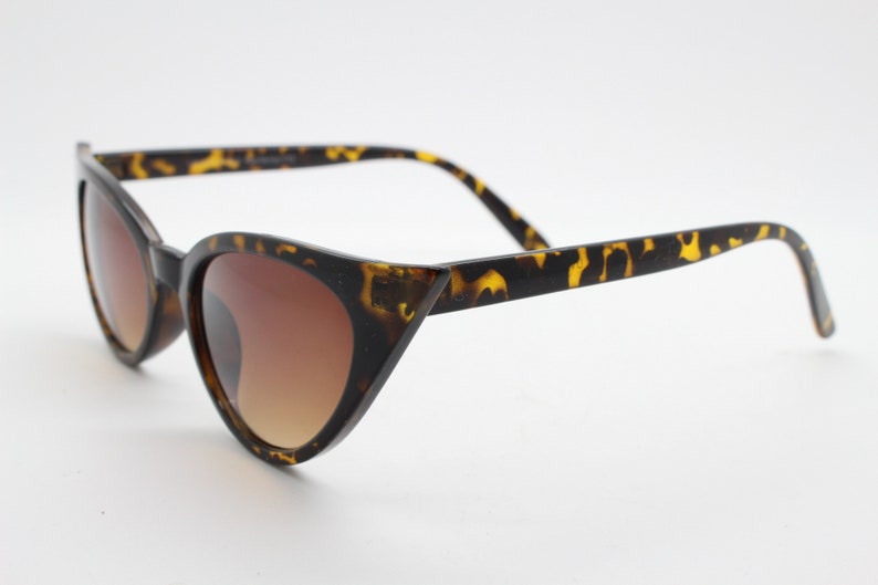May include: Tortoise shell cat eye sunglasses with brown gradient lenses.