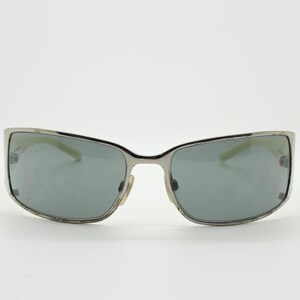 May include: Silver-framed sunglasses with gray lenses. The rectangular lenses are set in a silver frame with a slight curve. The sunglasses have a classic, understated design, suitable for everyday wear.