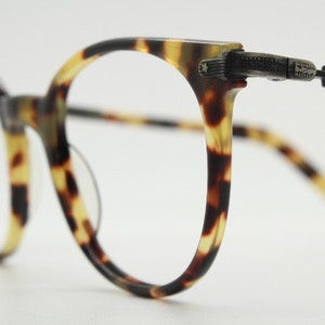 Puede incluir: Gafas de pasta de carey con montura metálica y detalle de estrella en la patilla.