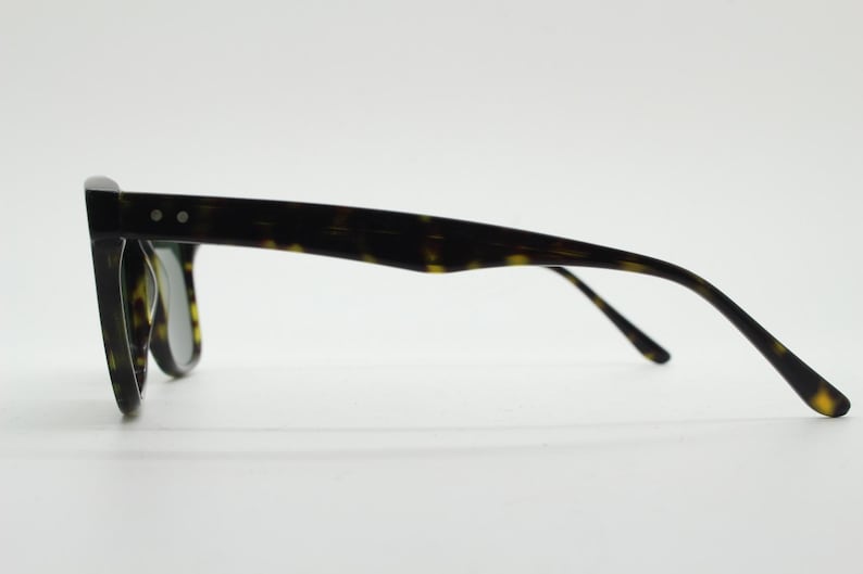 Puede incluir: Gafas de sol con montura de carey y lentes oscuras. Las gafas tienen un estilo cl&aacute;sico y retro.