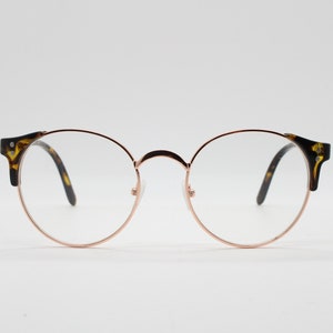 May include: Round tortoiseshell eyeglasses with a rose gold metal frame.