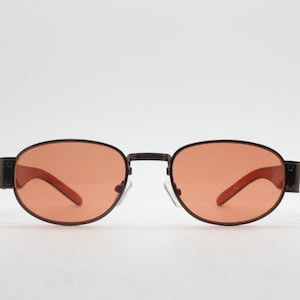 Lunettes de soleil à profil bas vintage des années 90. Monture en chrome marron avec branches épaisses en ambre transparent et verres orange. Inutilisé. BNWT