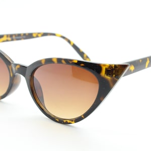 May include: Tortoise shell cat eye sunglasses with brown lenses.