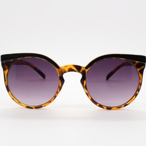 Può includere: Occhiali da sole tartaruga con montatura nera e lenti grigio scuro.