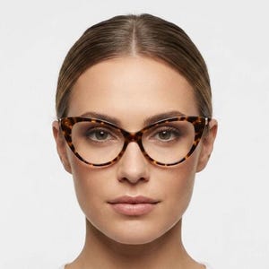 May include: Cat-eye glasses featuring a brown and black tortoiseshell pattern on the frame. The lenses are clear and oval-shaped, with a pointed outer edge that extends upwards. The frame is thin and lightweight, highlighting the distinct pattern.