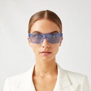 Könnte beinhalten: Blaue, getönte quadratische Sonnenbrille mit einem klaren Rahmen.