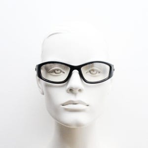 90s vintage sports sunglasses. Black matt aerodynamic wraparound with straight white rubber arms and light tone lenses. Y2K rave shield