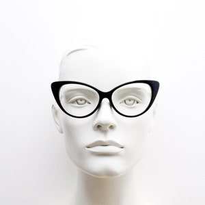 May include: A white mannequin head wearing black cat-eye glasses.