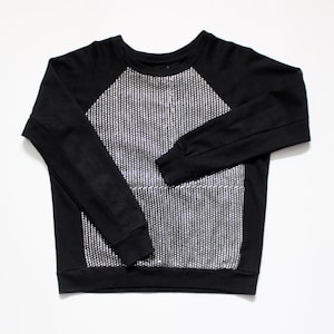 Può includere: Felpa nera a maniche lunghe con un design a righe bianche e nere sul davanti.