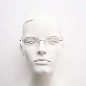 Frameless vintage oval eye glasses. Extremely minimal lightweight blue titanium optical frame with springy hingeless arms. 2000s