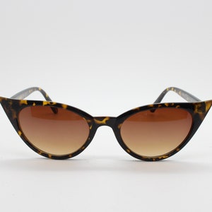 May include: Tortoise shell cat eye sunglasses with brown lenses.