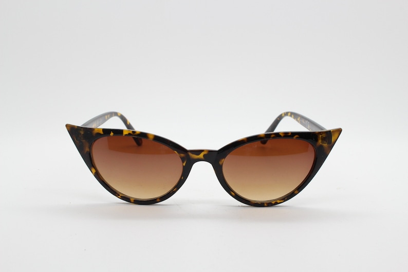 May include: Tortoise shell cat eye sunglasses with brown lenses.
