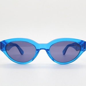 May include: Blue cat-eye sunglasses with a clear frame and dark lenses.