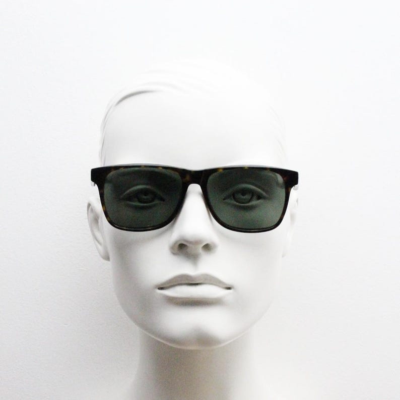 Puede incluir: Una cabeza de maniqu&iacute; blanca con gafas de sol de carey con lentes verdes.