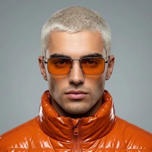 May include: Square-framed glasses with thin black metal rims and vibrant orange-tinted lenses. The eyewear features a double bridge design and adjustable nose pads, providing a clear view of the rectangular lens shape and the dark frame structure.