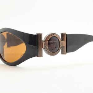 90s vintage oval sunglasses. Low profile black gloss frame with massive bronze metal arm crests and brown lenses. BNWT. Unworn NOS