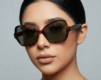 May include: Oversized butterfly-shaped sunglasses featuring a brown tortoiseshell pattern frame and dark green tinted lenses. The temples display the brand name Celine in small gold lettering near the hinges, which are accented with three metal dots.