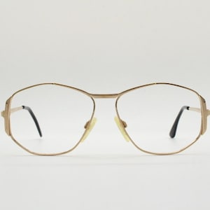 Puede incluir: Gafas de metal dorado con montura geom&eacute;trica y lentes transparentes.