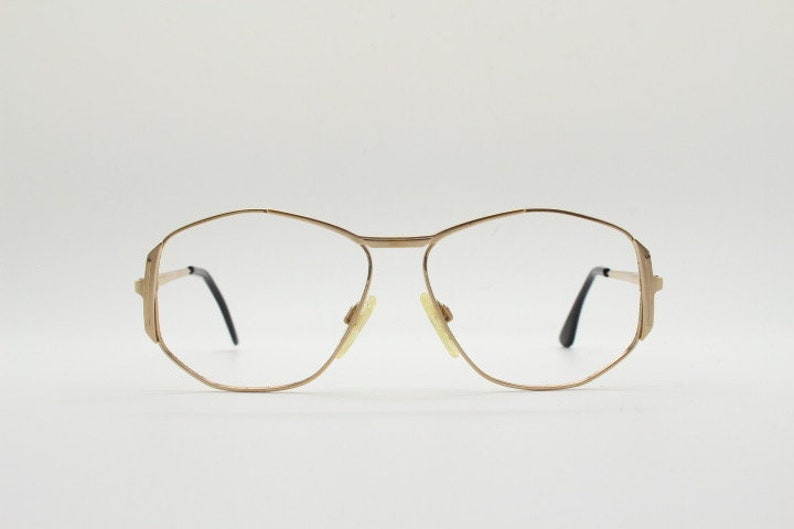 Puede incluir: Gafas de metal dorado con montura geom&eacute;trica y lentes transparentes.