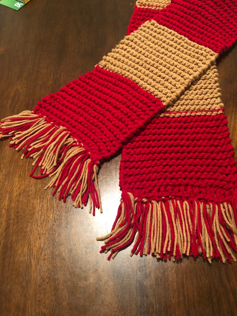 May include: A red and tan striped knitted scarf with fringe on the ends.