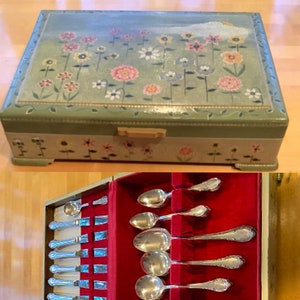 May include: A wooden box with a floral design on the lid, open to reveal a red velvet lined interior with a set of silver flatware.