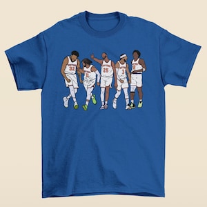 May include: A blue t-shirt featuring a graphic of five basketball players wearing orange and white jerseys with the text "New York" on the front. The players are in a line, facing forward, and appear to be celebrating.