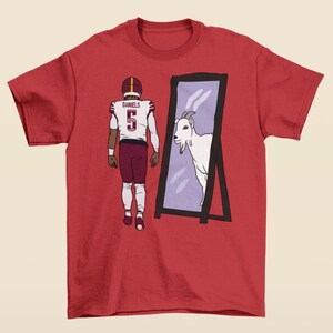 May include: Red t-shirt featuring a graphic of a football player looking in a mirror and seeing a goat. The player is wearing a maroon jersey with the number 5 and the name "DANIELS" on the back.