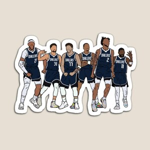 May include: A group of seven basketball players wearing blue and white uniforms with the word "Dallas" and their jersey numbers on the front. The players are standing in a line, facing forward, with their arms at their sides. The background is a light gray.