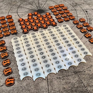 Puede incluir: Un conjunto de fichas de juego para un juego de mesa. Las fichas están hechas de plástico y tienen diferentes formas y colores. Hay fichas hexagonales naranjas, fichas redondas blancas con números negros y fichas en forma de media luna blancas con números negros.