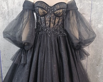 May include: A black tulle ball gown with a sweetheart neckline and a corset bodice. The gown has long, puffy sleeves and a full skirt. The bodice is adorned with lace and beading.