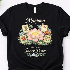 May include: Black t-shirt with a watercolour design featuring the word "Mahjong" above a lotus flower and Mahjong tiles. The text "brings me Inner Peace" is below the design. The design includes blue and orange floral accents.