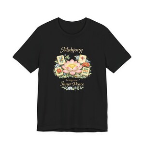 May include: Black t-shirt with a floral design and the text "Mahjong brings me Inner Peace." The design includes a lotus flower and Mahjong tiles. The shirt is a short-sleeved crew neck.