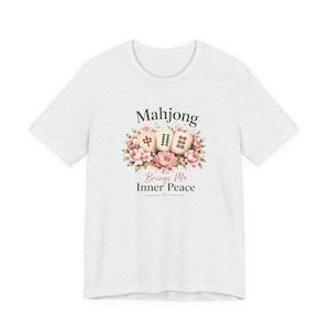 May include: A light gray t-shirt featuring a floral design with three Mahjong tiles and the text "Mahjong Brings Me Inner Peace". The design includes pink and green floral elements.