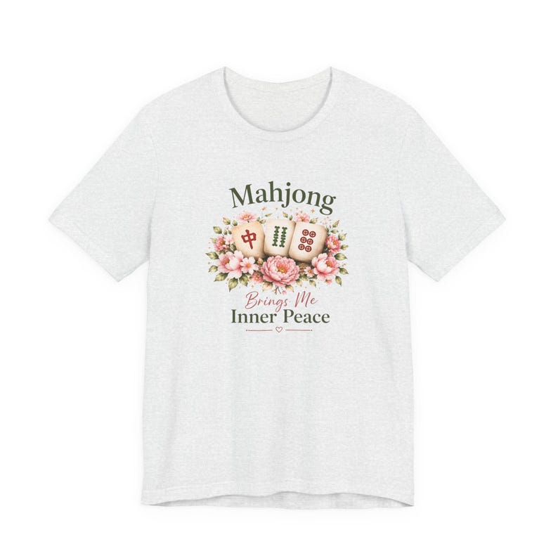 May include: A light gray t-shirt featuring a floral design with three Mahjong tiles and the text "Mahjong Brings Me Inner Peace". The design includes pink and green floral elements.