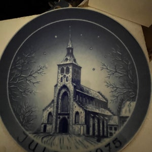 May include: A blue and white Christmas plate featuring a church with a tall steeple and the text "Julen 1975".